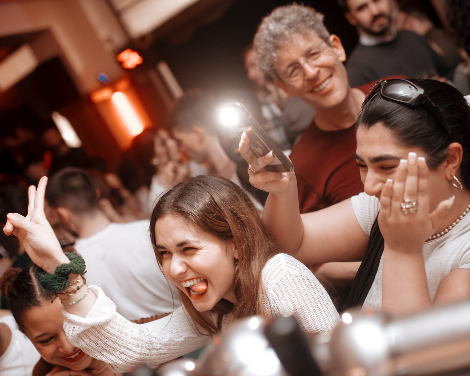 A joyful, laughing crowd pressed close together at a lively indoor party.